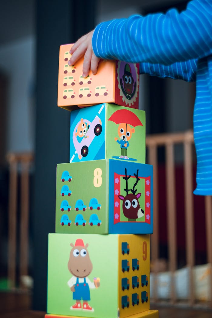 our-story A child playing indoors, stacking colorful wooden toy blocks with joyful illustrations.