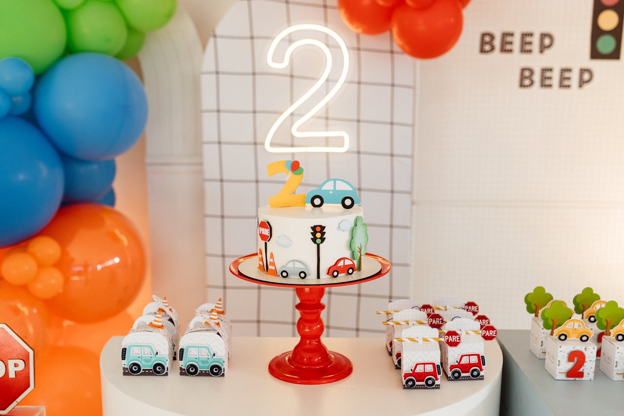gallery-02 A vibrant birthday celebration setup with a traffic-themed cake and colorful balloons for a second birthday party.